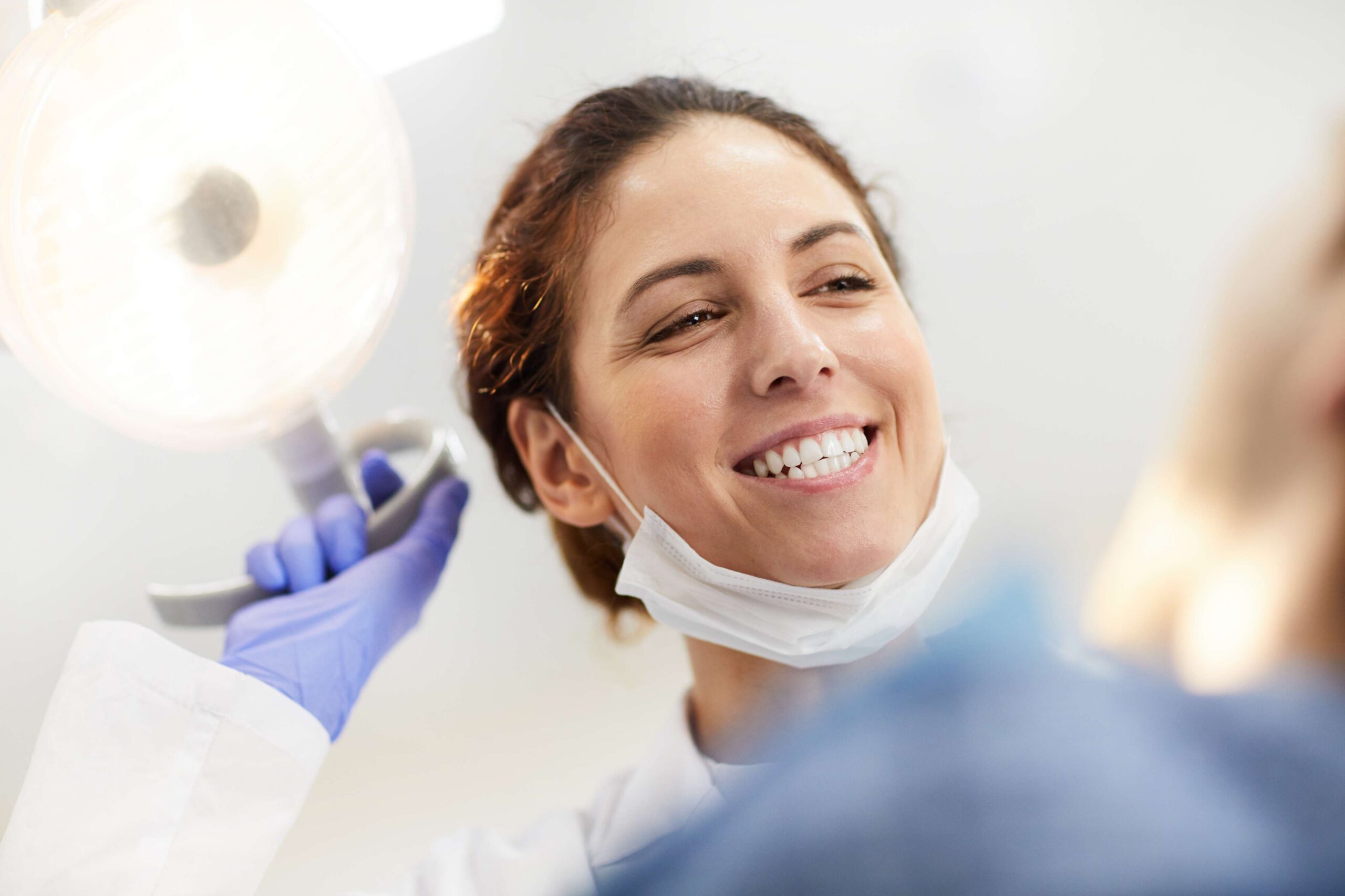 miling dentist speaking with a patient during an exam.