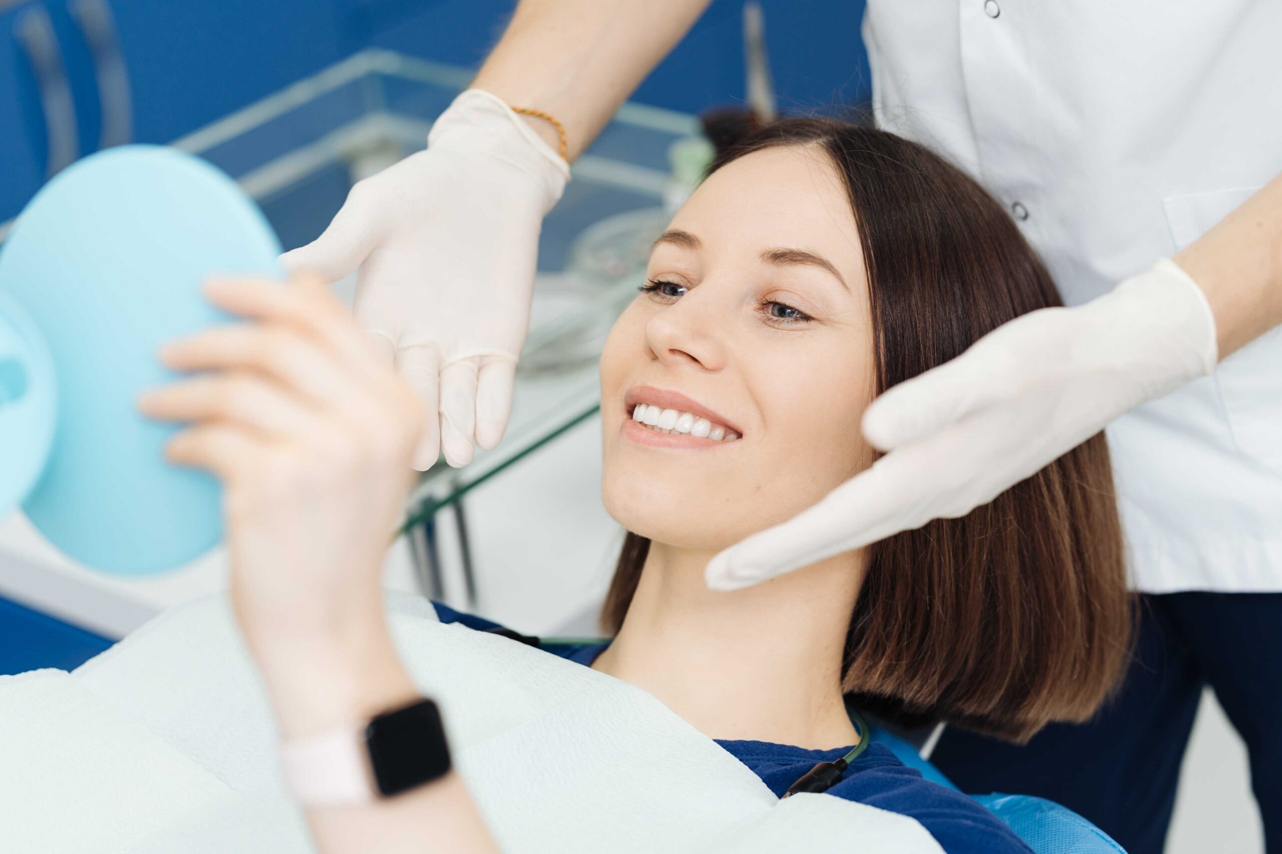 Smiling patient checking her smile in a hand mirror.